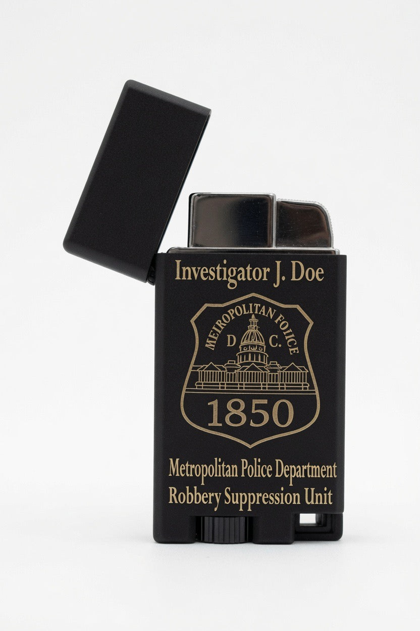A black lighter with its cap open, featuring gold-colored text and emblem that reads 'Investigator J. Doe' and 'Metropolitan Police Department Robbery Suppression Unit 1850'.